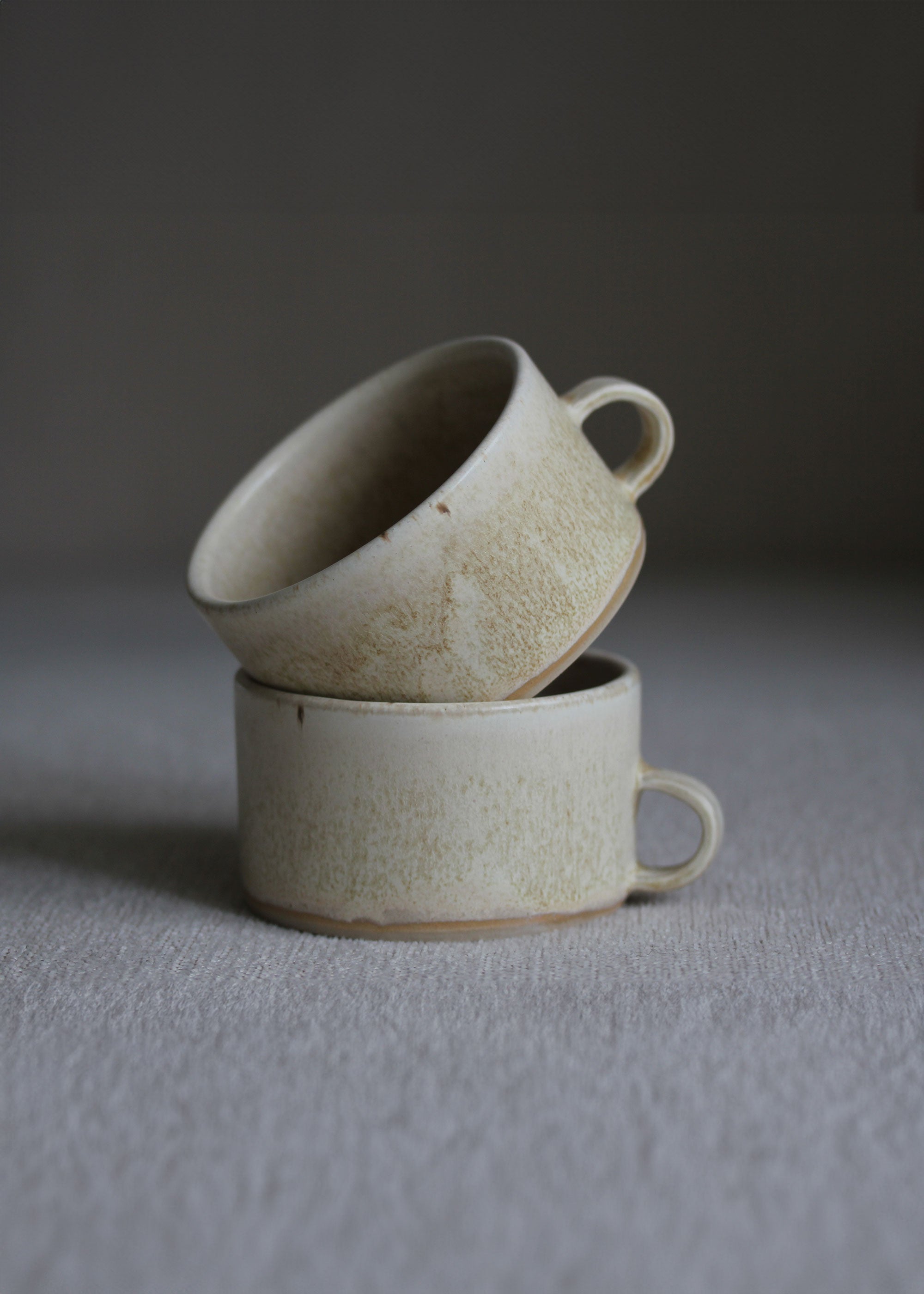 Zwei kleine Kaffeetassen in Beige mit Henkel ineinander gestellt