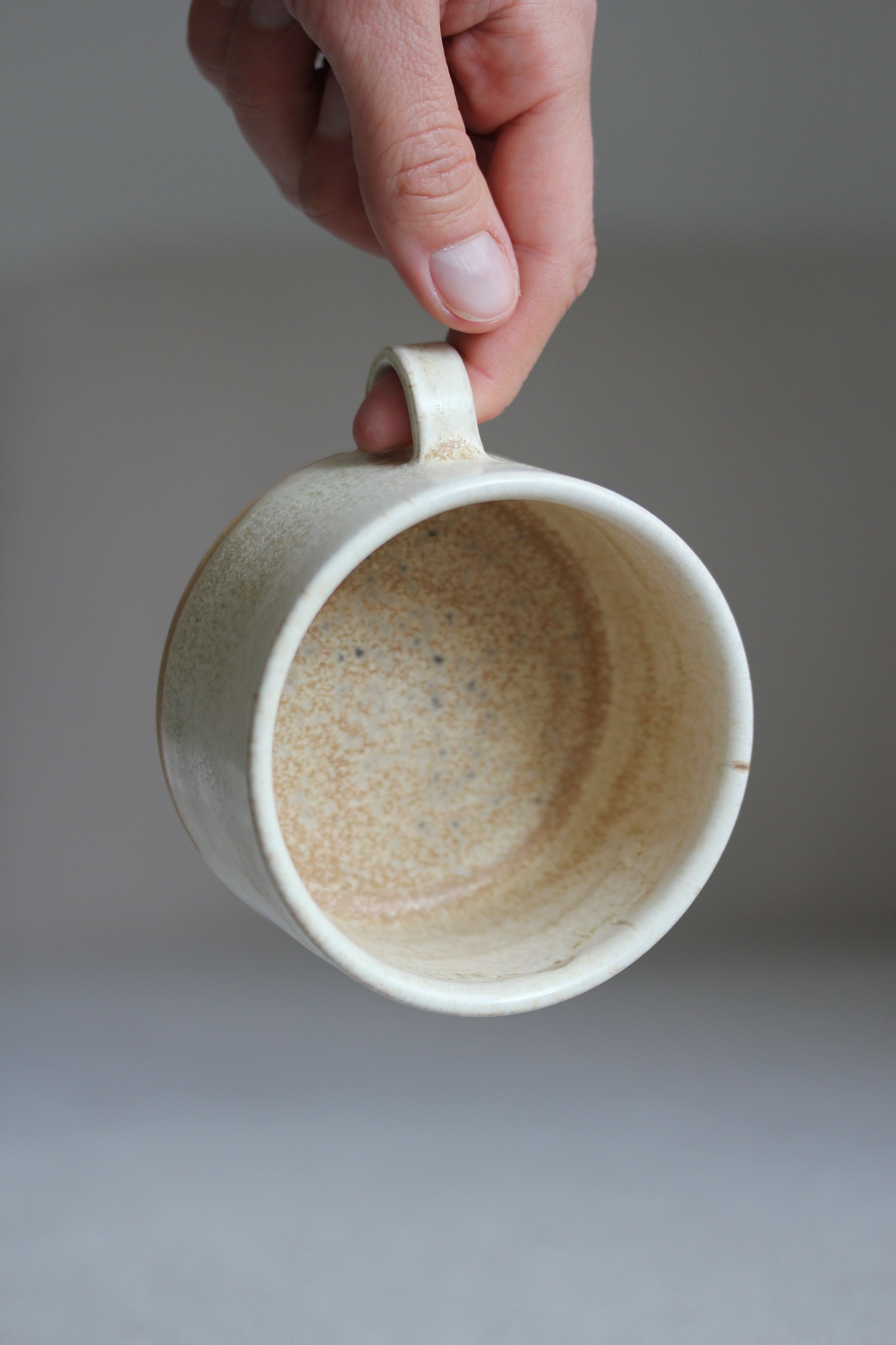 Hand hält kleine Kaffeetasse in Beige mit Henkel