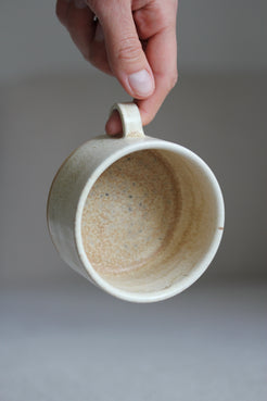 Hand hält kleine Kaffeetasse in Beige mit Henkel