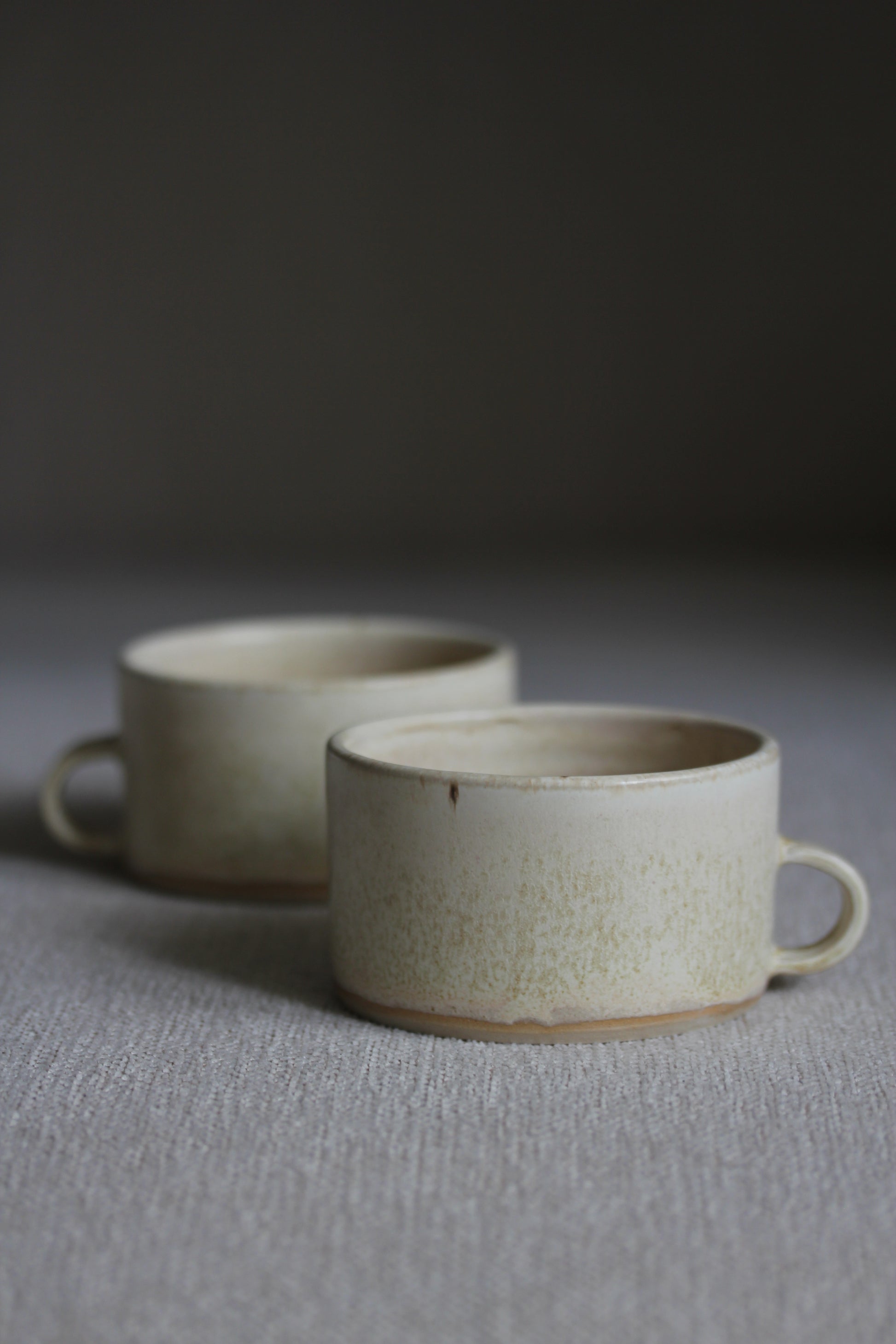 Zwei kleine Kaffeetassen in Beige mit Henkel nebeneinander stehend