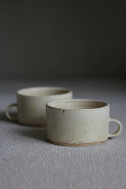 Zwei kleine Kaffeetassen in Beige mit Henkel nebeneinander stehend