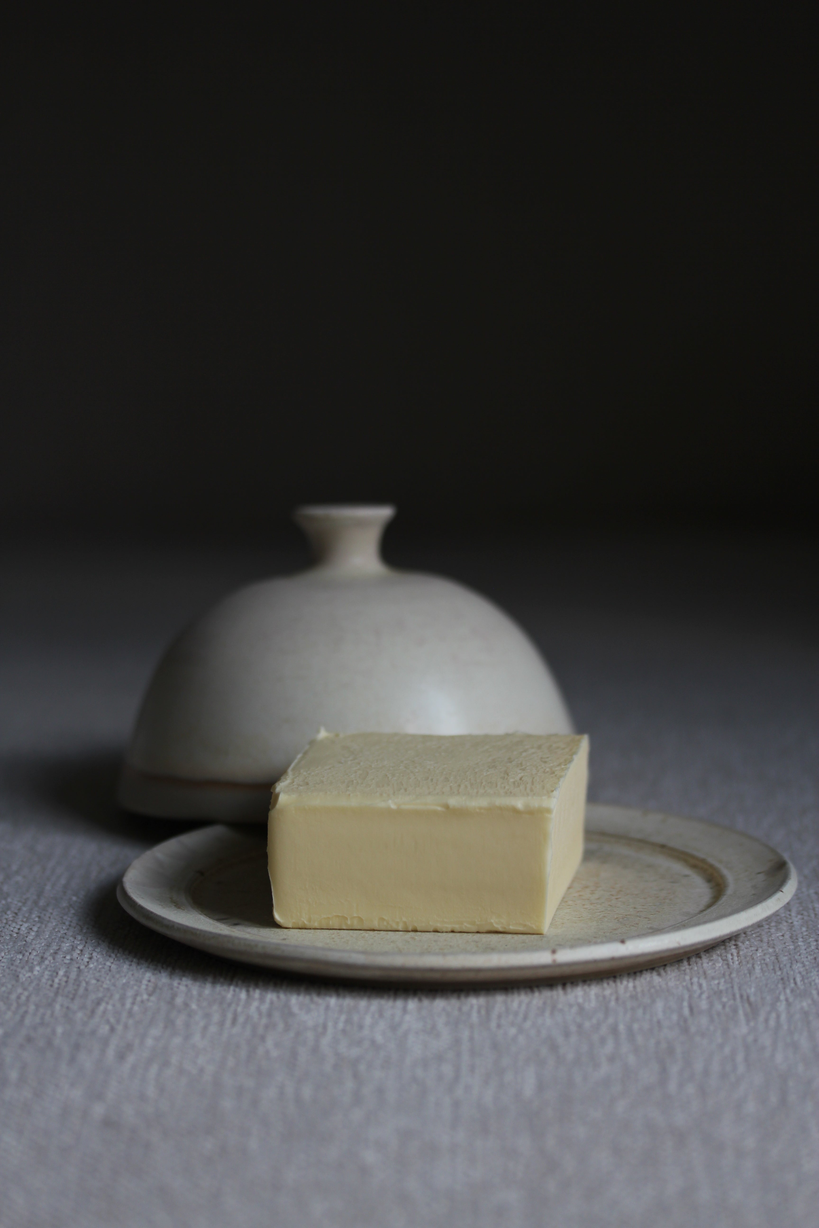 Geöffnete Butterdose in Beige auf der ein Stück Butter liegt