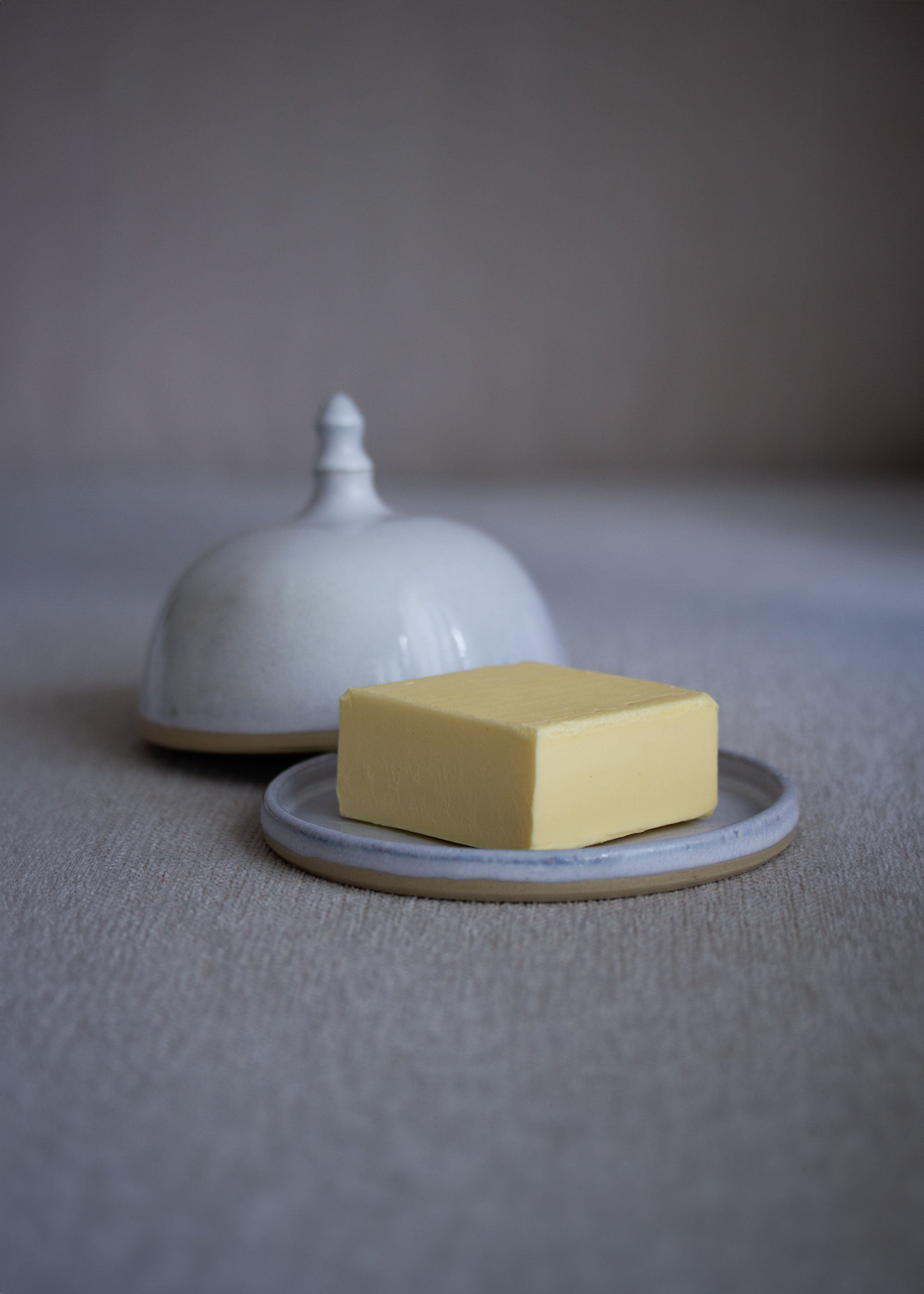 Geöffnete, runde Butterdose in zartem Eisblau mit einem Stück Butter belegt