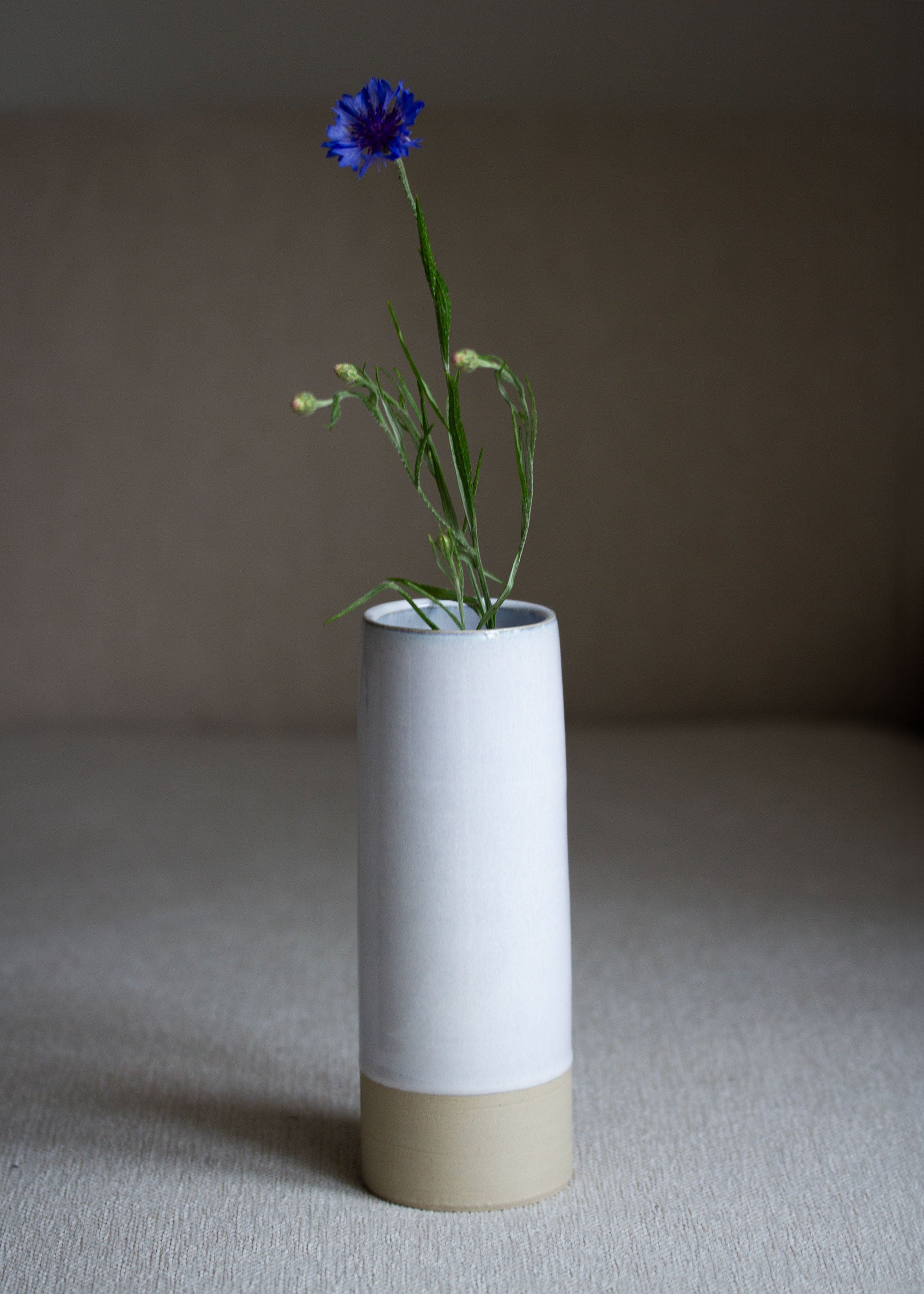 Schmale Vase in zartem Eisblau mit abgesetztem braunen Rand am Boden mit Kornblume