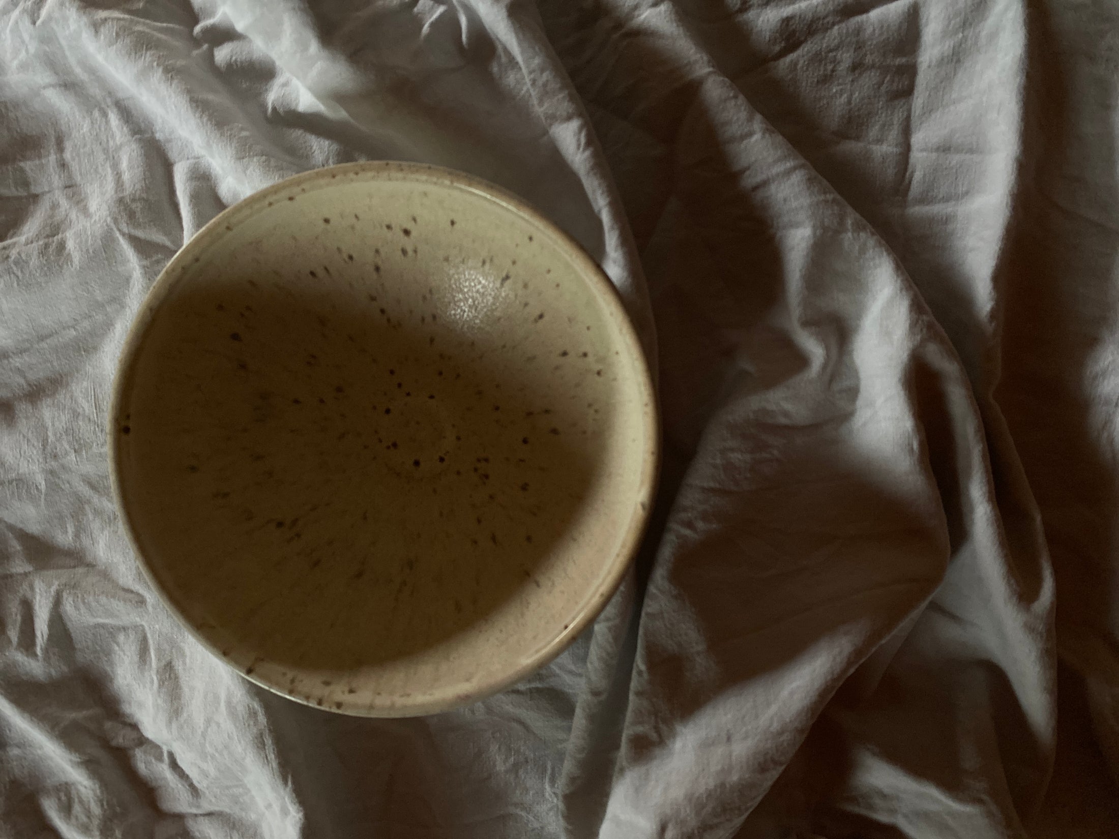 Beige gesprenkelte Schale von oben auf Tuch