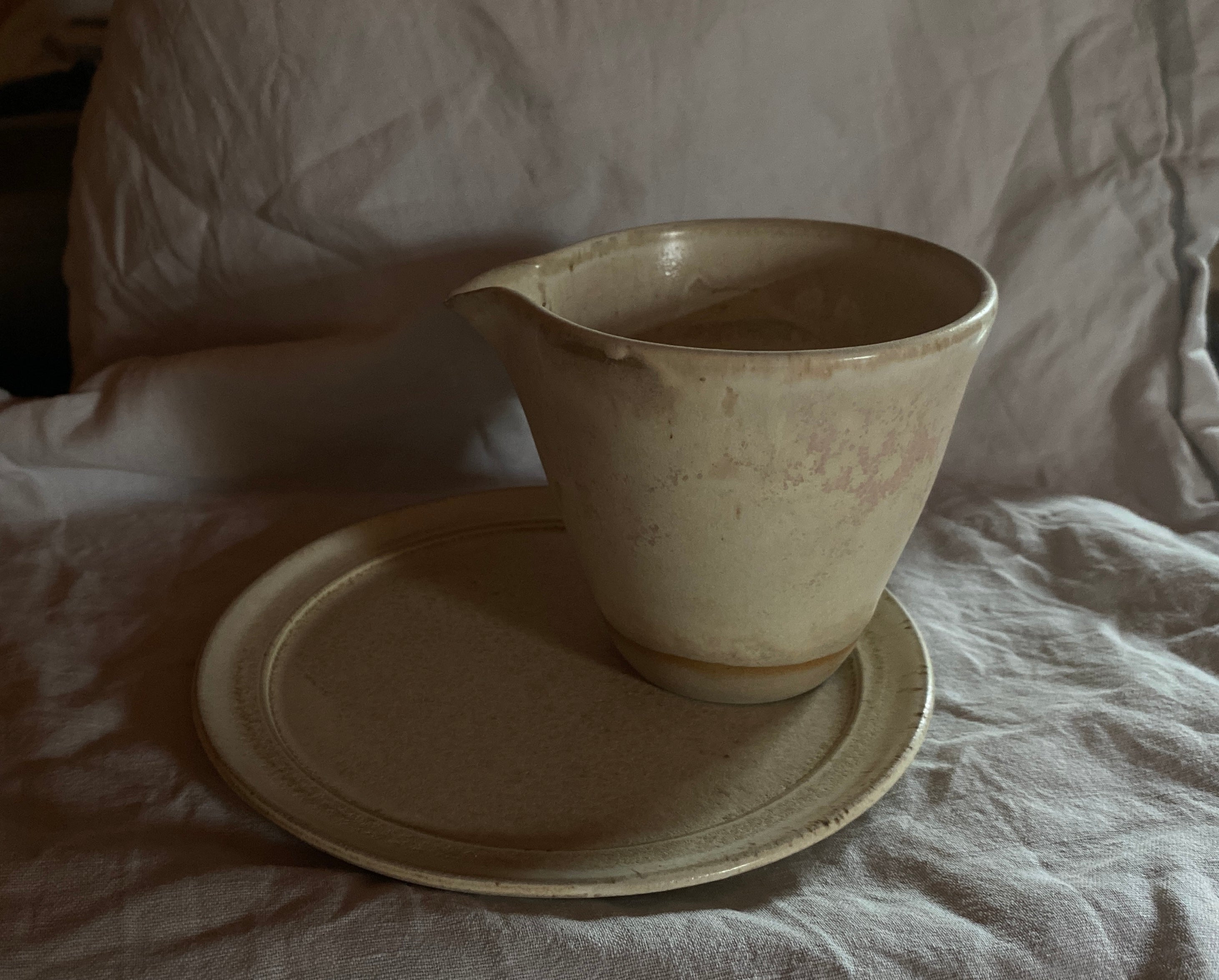 Kleines Milchkännchen in Beige auf Teller in Beige